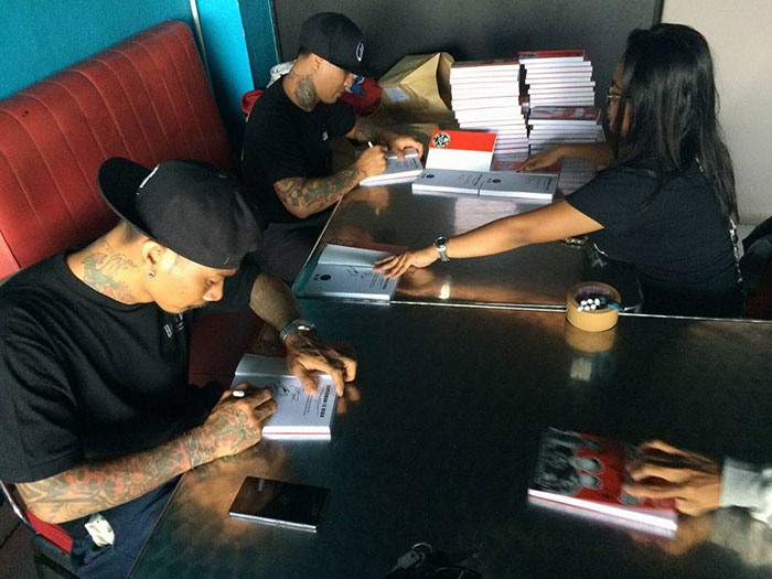 JRX dan Jon Eka Rock sedang sibuk membubuhkan tanda tangan di buku-buku edisi khusus untuk Punk Rock Boat. | Foto: Bobby Kool.